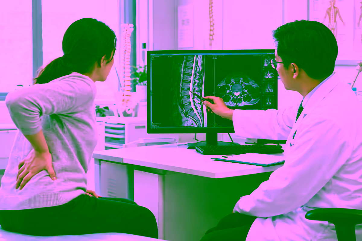 Bệnh nhân đau lưng trao đổi với bác sĩ bên cạnh phim MRI cột sống