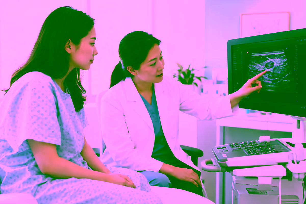 Bác sĩ giải thích kết quả siêu âm tuyến vú cho bệnh nhân mặc áo choàng khám