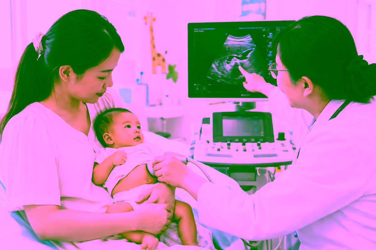 Bác sĩ nhi khoa siêu âm gan mật cho em bé được mẹ bế
