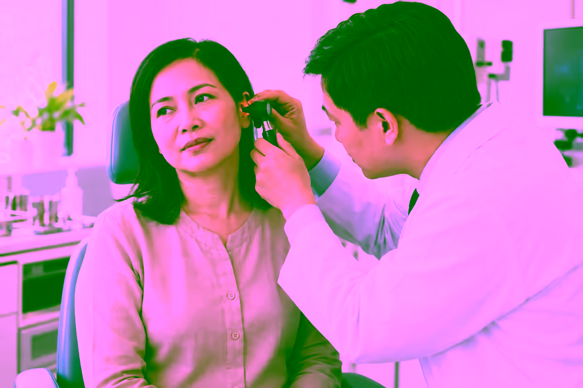 Bác sĩ tai mũi họng khám tai cho người bệnh bằng đèn soi
