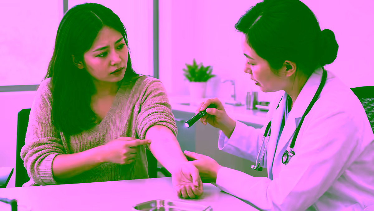 Bác sĩ da liễu kiểm tra vùng tím hơi nổi trên cẳng tay người bệnh