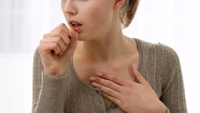 Người phụ nữ ôm ngực và ho do phản ứng kích ứng đường thở trong bệnh bụi phổi bông
