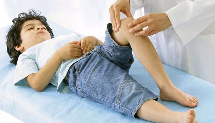 Bác sĩ chuyên khoa đang khám khớp gối và kiểm tra tầm vận động chân cho trẻ em