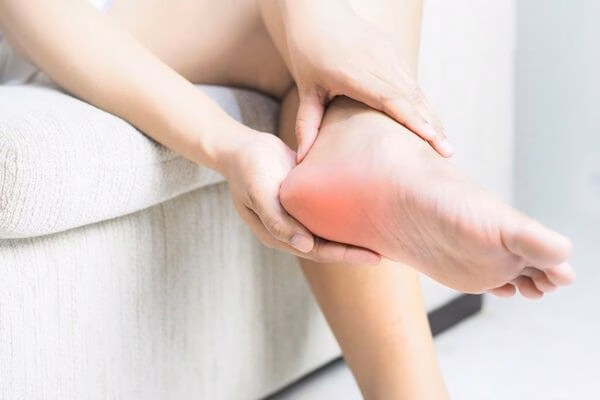 Người bệnh dùng hai tay xoa bóp vị trí gót chân bị đau nhức và sưng đỏ