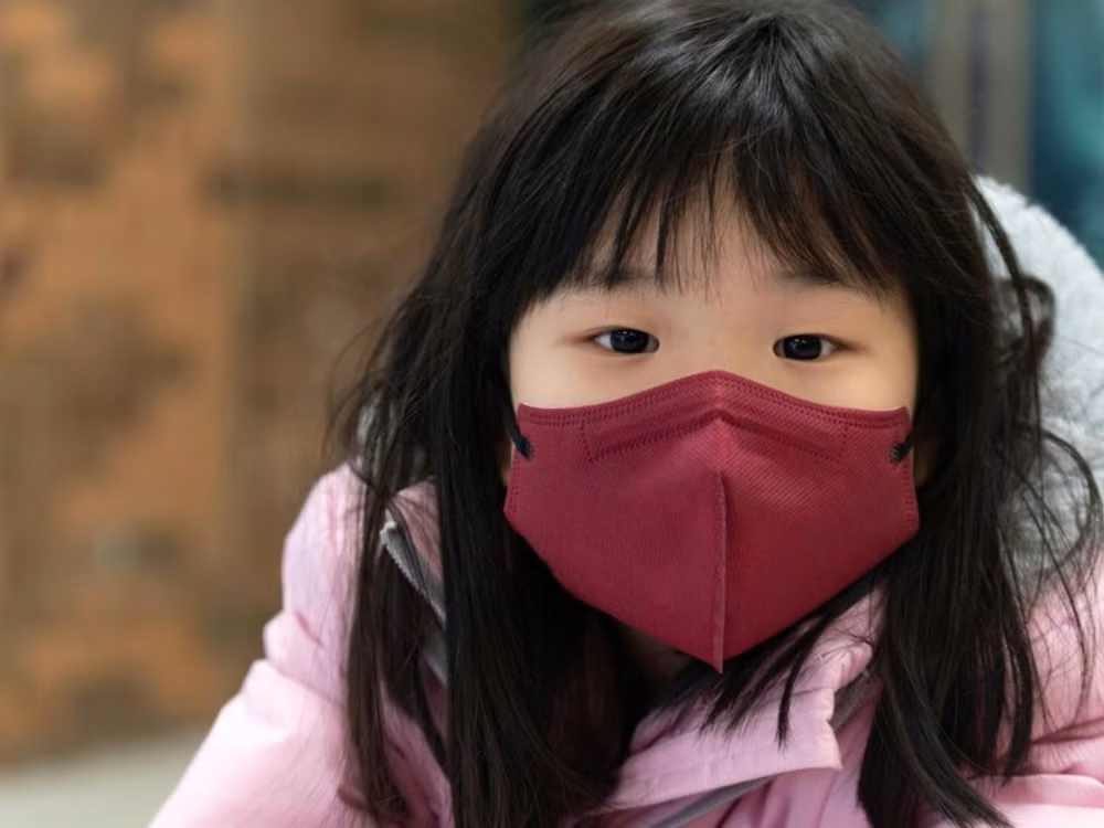 Bé gái đeo khẩu trang y tế giúp phòng ngừa lây nhiễm virus cúm trong mùa lạnh