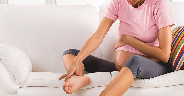 Người phụ nữ mang thai thực hiện động tác kéo giãn cơ bắp chân nhẹ nhàng giúp thư giãn trước khi ngủ