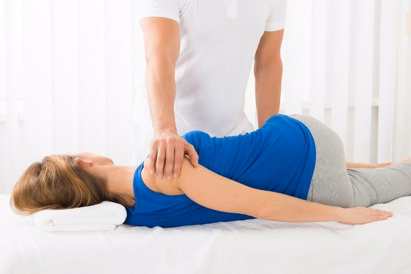 Kỹ thuật viên y tế hỗ trợ người bệnh tập phục hồi chức năng sau khi điều trị sai khớp