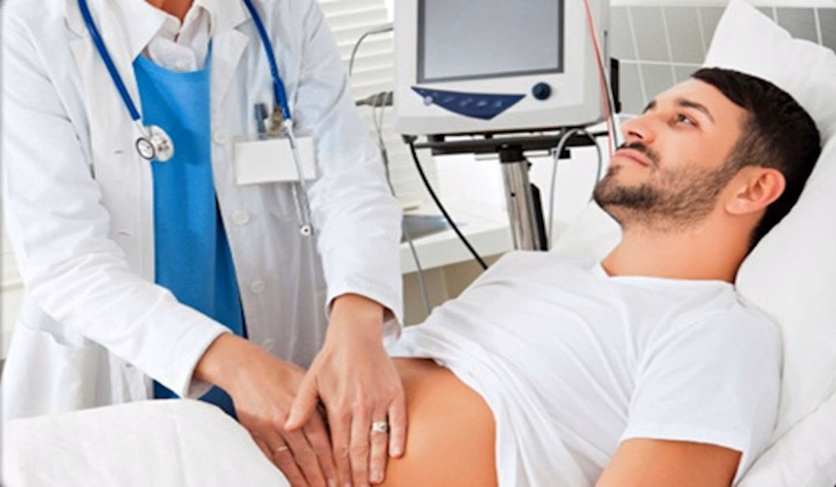 Bác sĩ tiến hành thăm khám sờ nắn lâm sàng vùng bụng cho bệnh nhân nam nằm trên giường bệnh
