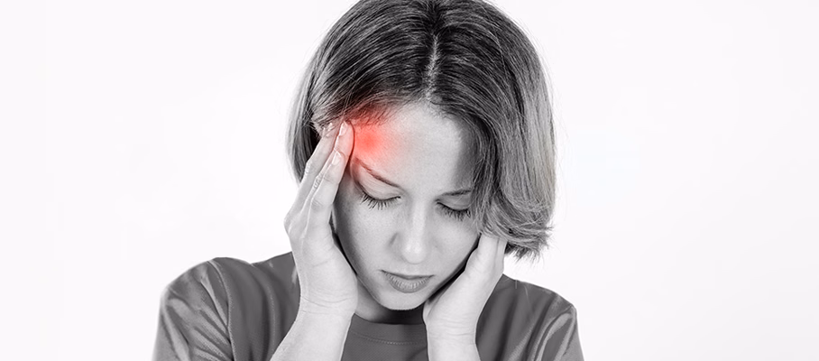 Người phụ nữ nhắm mắt ôm đầu vì đau nhức và nhạy cảm với ánh sáng âm thanh