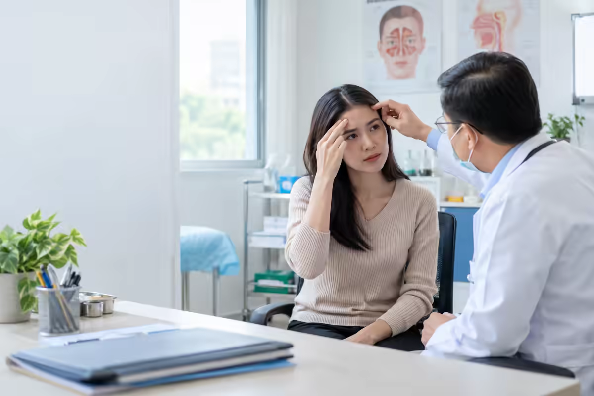 Người bệnh xoa vùng trán lông mày và được bác sĩ thăm khám nguyên nhân đau