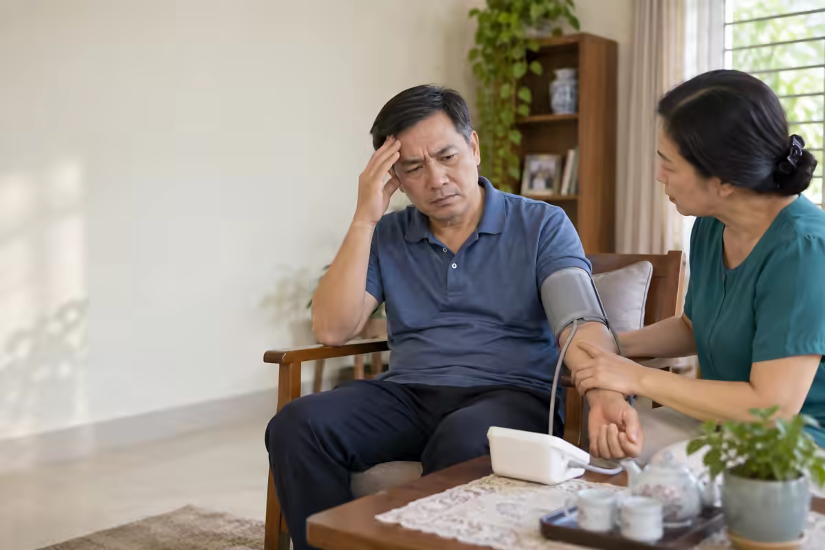 Người bệnh đau đầu nhẹ được người nhà đo huyết áp và theo dõi dấu hiệu cảnh báo