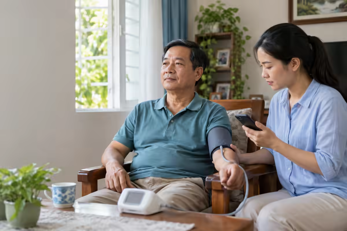 Người bệnh ngồi nghỉ và được người nhà đo huyết áp đúng cách tại nhà