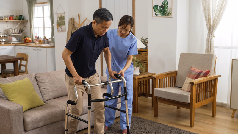 Người bệnh sau đột quỵ đang kiên nhẫn tập đi cùng khung tập đi walker dưới sự hướng dẫn an toàn
