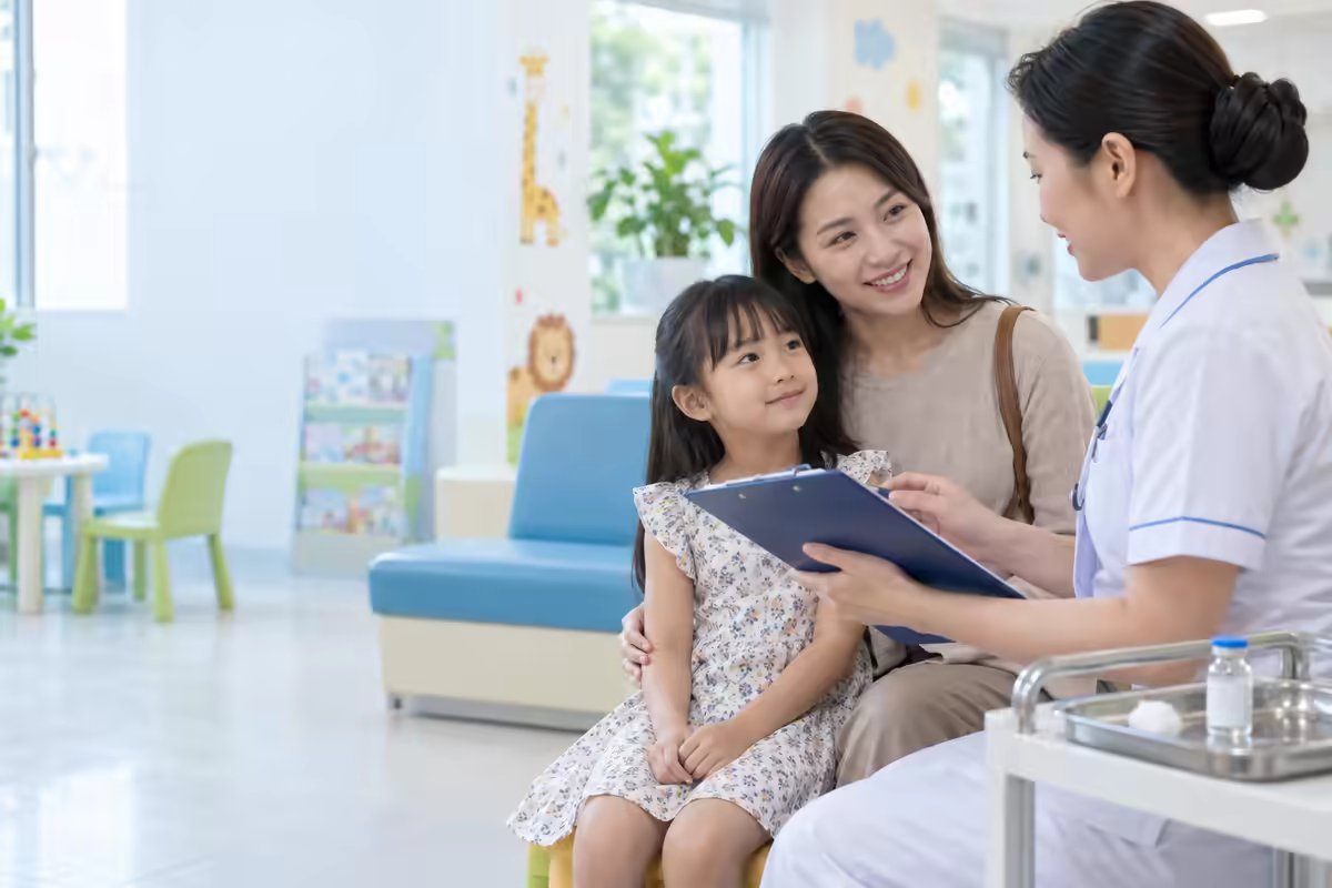 Cha mẹ đưa trẻ đến điểm tiêm và được nhân viên y tế tư vấn vắc xin thủy đậu