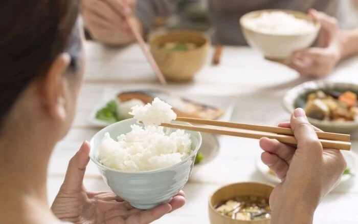 Người đang cầm bát cơm trắng trong bữa ăn gia đình